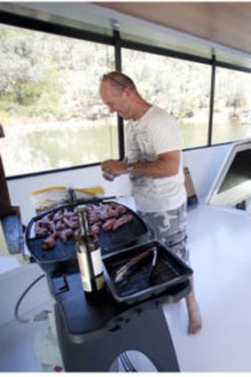 Noel Courtney upstairs on their Lake Eildon houseboat cooking a BBQ lunch.