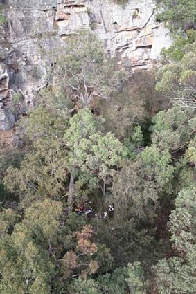 Rescuers reach a boy who fell 80 metres down a cliff in the Watagan State Forest. 