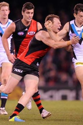 Port's Jasper Pittard kicks as Essendon's Brendon Goddard launches himself to try and smother.