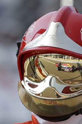 Mirror, mirror: Sebastian Vettel's car is reflected in a firefighter's visor.