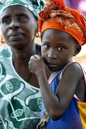A young girl listens while her mother attends a meeting of women from several communities in Senegal that are eradicating female genital mutilation.