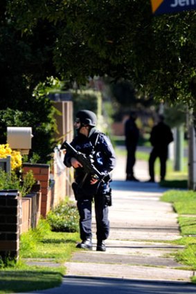 An armed police officer patrols the street near the siege.