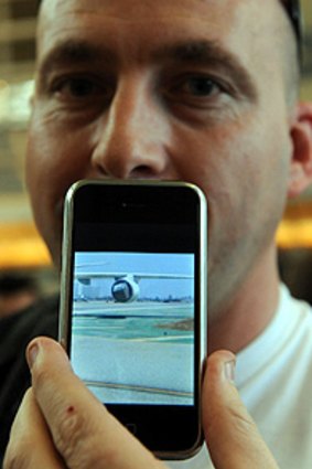 Michael Charlton from Kansas shows an image of the damaged engine on his iPhone after he was evacuated with other passengers from Japan Airlines flight 61 to Tokyo. Photo: AFP PHOTO/Mark Ralston