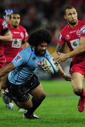 Quade Cooper of the Reds prepares to do a flick pass before he is tackled by Tatafu Polota-Nau of the Waratahs during the round 18 Super Rugby match between the Queensland Reds and the NSW Waratahs at Suncorp Stadium on July 14, 2012 in Brisbane, Australia.