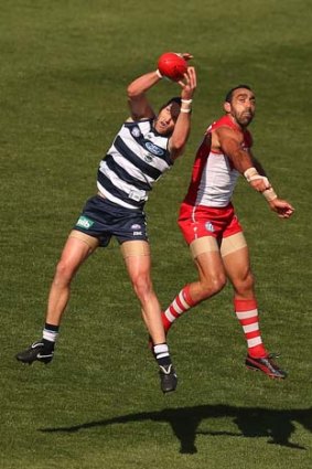 Harry Taylor of the Cats takes a mark as Adam Goodes of the Swans leaps up to contest.
