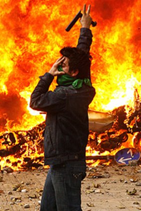 Fiery protest: An opposition supporter gestures as a police motorcycle burns in Tehran.
