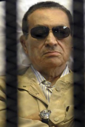 Former Egyptian President Hosni Mubarak sits inside a cage in a courtroom in Cairo.