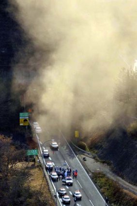 Smoke billows from the entrance of the collapsed Sasago tunnel