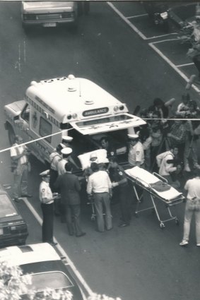 Ambulance workers and police surround a victim of the Queen Street Shooting before they're loaded into an ambulance.