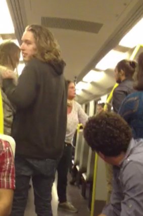 The woman, in white shirt and jeans, can be seen confronting a man of African background on the train.