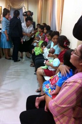 Nannies hold some of the nine babies alleged to be the surrogate children of one Japanese man after a police raid at a Bangkok apartment.