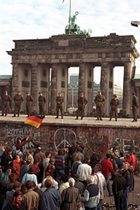 East German border guards standing on top of the Berlin wall in front of the Brandenburg Gate on November 11, 1989.