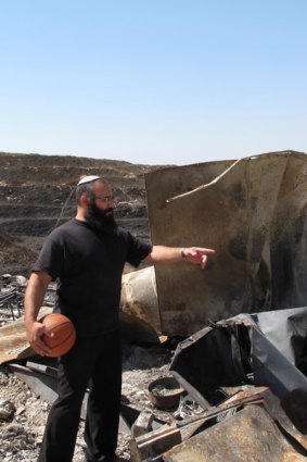 Yehuda Shimon, 34, a resident of the West Bank illegal outpost Havat Gilad stands among the  ruins of a caravan home that was destroyed by a fire allegedly lit by Palestinians from a nearby village.