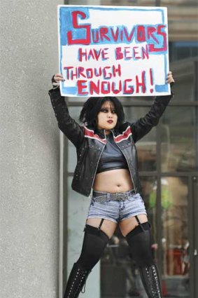 Carmen Chan holds up a sign in front of police headquarters in Toronto, Canada
