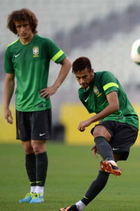 Neymar curls a ball in as  David Luiz (L) looks on during a training session in Fortaleza.