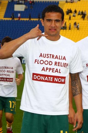 Tim Cahill poses with a t-shirt showing his support for the flood victims of Queensland.