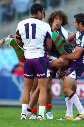 Michael Crocker of the Rabbitohs is upended by a swarm of Storm defenders.