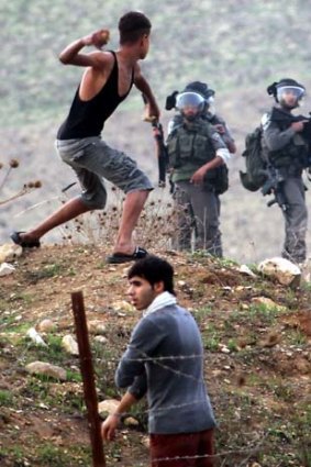 Tension &#8230; a Palestinian youth throws a rock at Israeli soldiers in the West Bank town of Nablus to protest military action on Gaza.