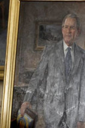 Former President George W. Bush stands next to his official portrait in the East Room at the White House.