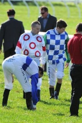 Jockeys and stewards inspect the track after race three.