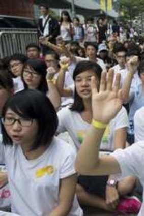 A secondary school student holds up a hand with a yellow ribbon tied around her wrist.