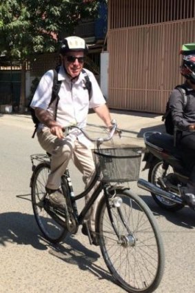 The writer hunched on a too-small bicycle as he practices on the back streets of Phnom Penh.