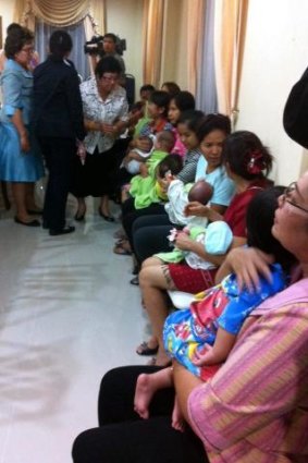 Nannies hold some of the nine babies alleged to be the surrogate children of one Japanese man, after a police raid at a Bangkok apartment.