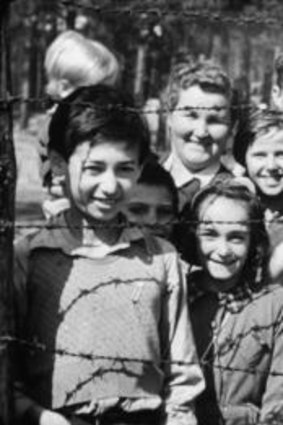 Smiling children through barbed wire.  Still from footage shot by Sergeant Lewis or Sergeant Lawrie, 18-20 April 1945.