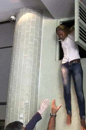 A woman escapes via an air vent where she was hiding during an attack by masked gunmen at a shopping mall in Nairobi.
