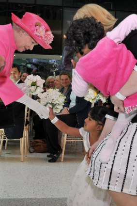 Her Majesty accepts a bouquet from former conjoined twin Trishna, guardian Moira Kelly holds Krishna.