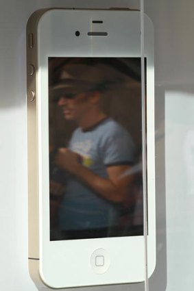 A pedestrian is reflected in a display of the new Apple iPhone 4Gs.