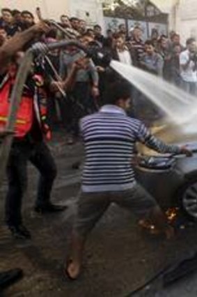 Palestinians help extinguish the fire after an Israeli airstrike on the car of Ahmad al-Jabari  in Gaza City.