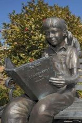 Bronze statues, including one of a young girl reading <i>To Kill a Mockingbird</i> are on the grounds of the old Monroe County Courthouse in Monroeville, Alabama. 
