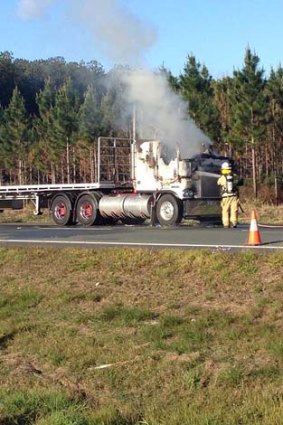A firefighter douses the flames coming from a truck on the Bruce Highway.