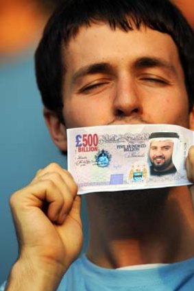 A Manchester City fan holds a fake British pound note with the face of Sheikh Mansour bin Zayed Al Nahyan after he bought the club in 2008.