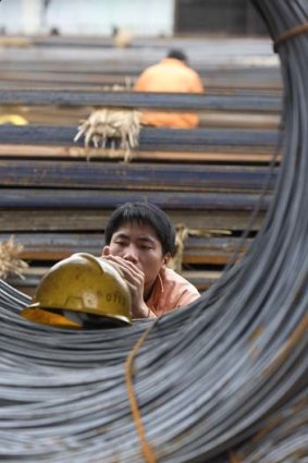 A worker rests near bales of steel rod in Shanghai.