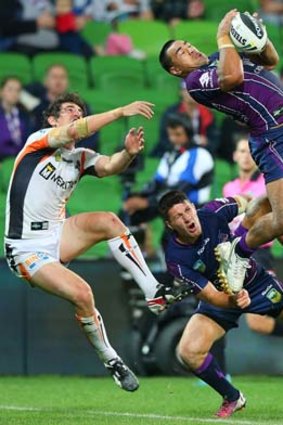 Mahe Fonua of the Storm catches the ball over Joel Reddy of the Tigers and teamate Gareth Widdop.