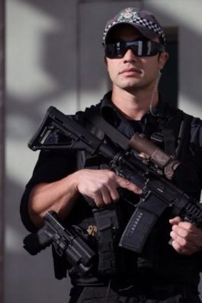 An armed AFP officer stands guard outside Parliament House.