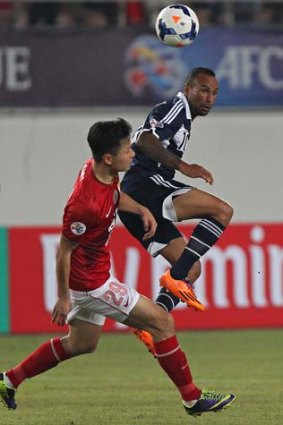 Archie Thompson of Melbourne Victory in action with Gao Lin of Guangzhou Evergrande.