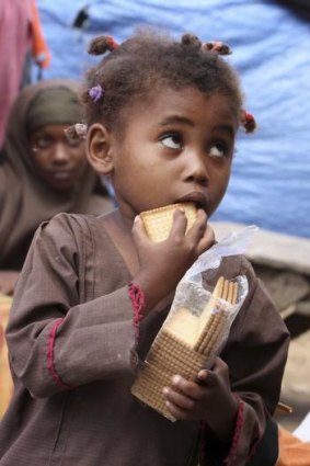 An internally displaced Somali child eats biscuits outside their makeshift shelters at a settlement near Mogadishu.