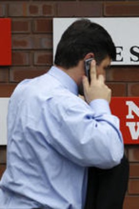 A man passes a sign outside the News International Limited.