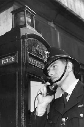 1968: A constable using one of the London police telephone boxes, which are for emergency and routine calls.