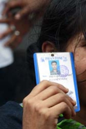 Hoping for survivors: A woman holds her husband's identity picture.