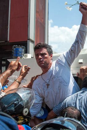 Flower power: Opposition leader Leopoldo Lopez is escorted into a vehicle after he turned himself in.
