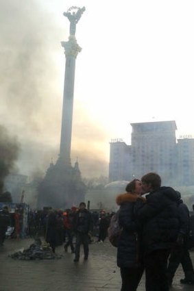 A young couple embrace as smoke rises above Independence Square.