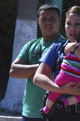 A police officer holds the seven-month-old baby girl who survived the Ciudad Juarez shooting.