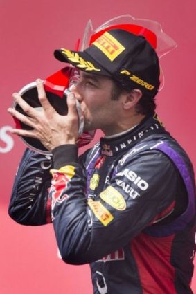 Daniel Ricciardo kisses his trophy on the podium.