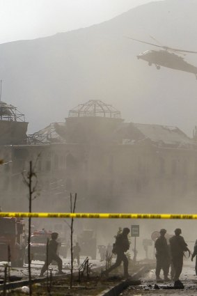 A NATO helicopter flies over the site of a bomb blast in Kabul.