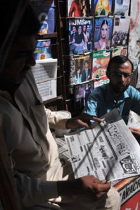 Front page...a Karachi man reads an Urdu-language newspaper report on the capture of the Taliban commander Mullah Baradar.