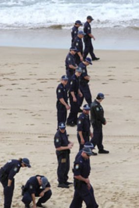 Police search ... officers scour the beach for clues; the woman was found with no identification.